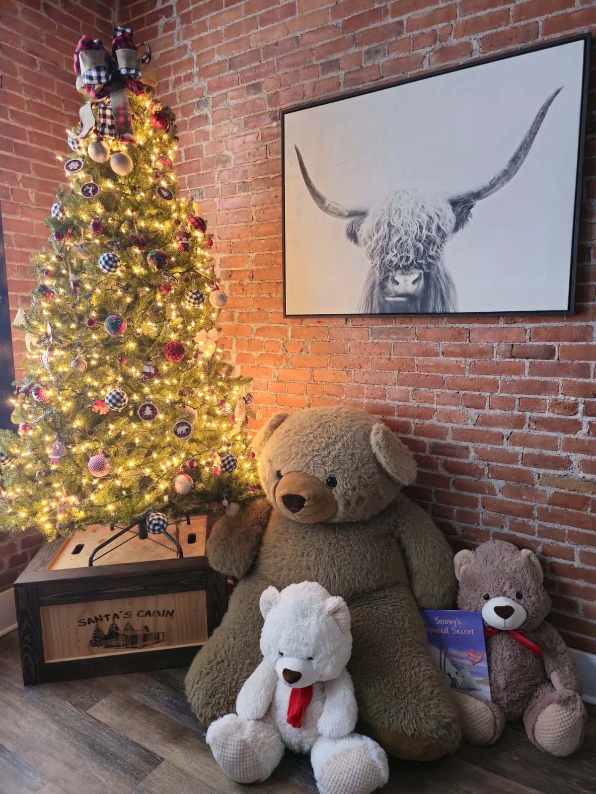 A living room decorated for the holidays, featuring a Christmas tree adorned with ornaments, plush stuffed bears, festive artwork, and a crate labeled 'SANTA'S CABIN.' The playful scene is filled with warmth and nostalgia, perfect for winter festivities.