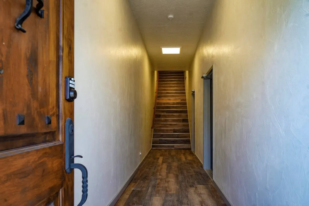 A welcoming entryway featuring a modern front door, staircase, and rich wooden flooring. The space exudes a sense of arrival, inviting guests to step inside and transition from the bustling street to a secure, private retreat.