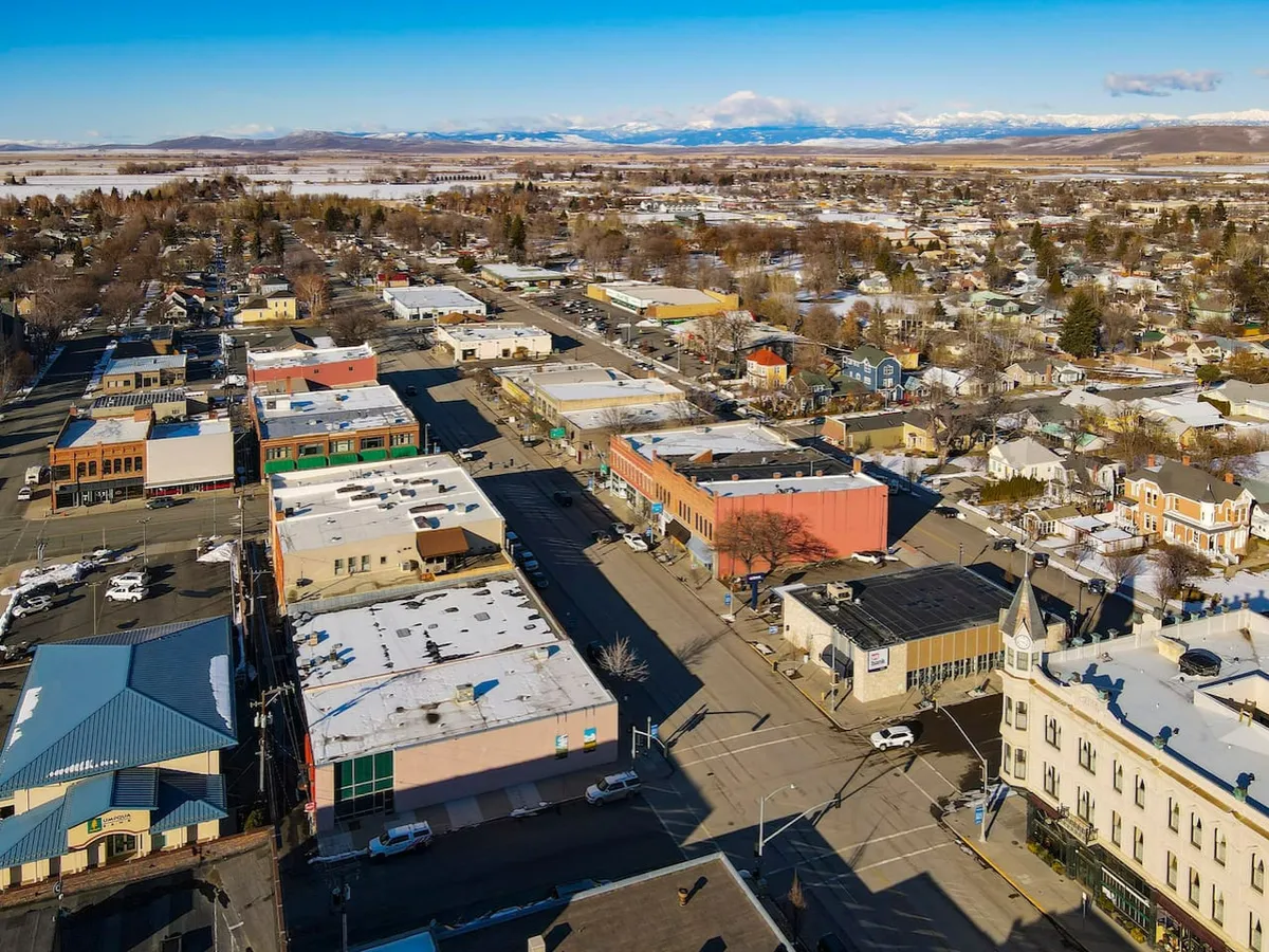 This image showcases vibrant and colorful storefronts along a snow-dusted, tree-lined street with distant mountains in the background. Shoppers can be imagined exploring boutiques and local eateries, and the lively atmosphere suggests a welcoming, walkable downtown with a sense of community year-round.